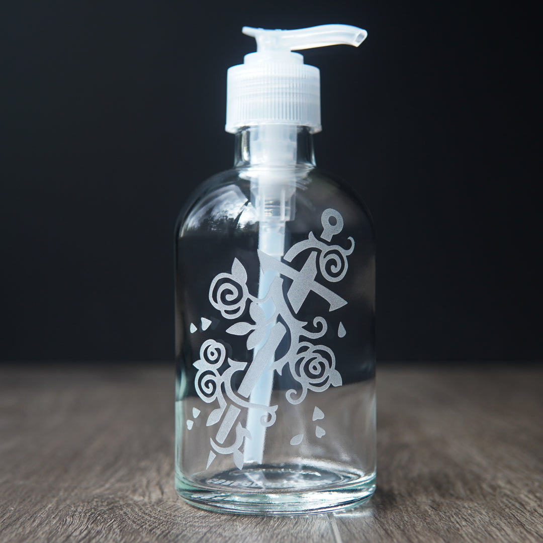 glass soap dispenser engraved with a sword wrapped with a rose vine.