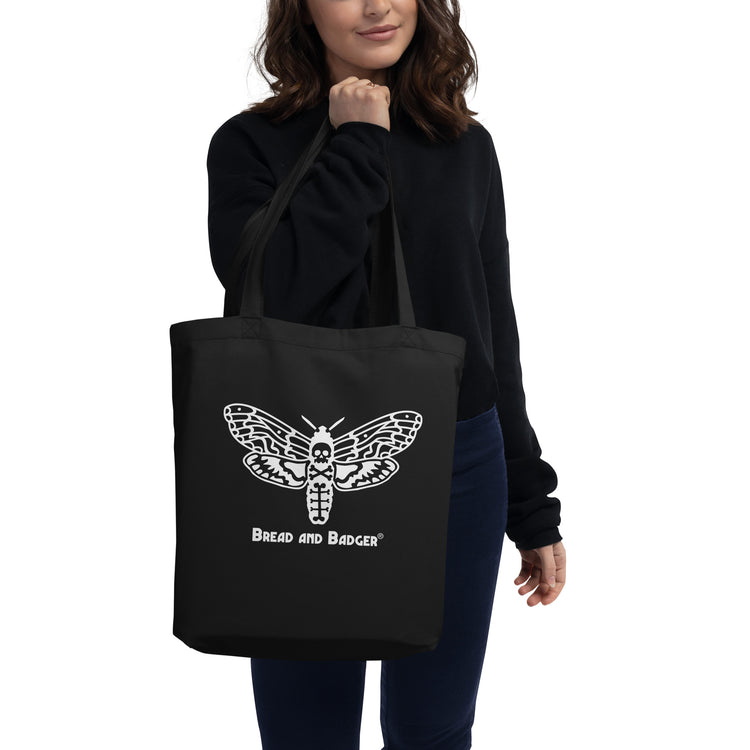 Person holding a black tote bag with a deaths head hawkmoth design and 'Bread and Badger' text.