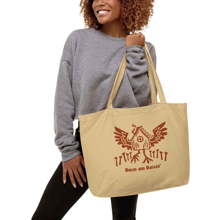 Woman holding a beige tote bag with red Baba Yaga's hut graphic and 'Bread and Badger' text on a white background