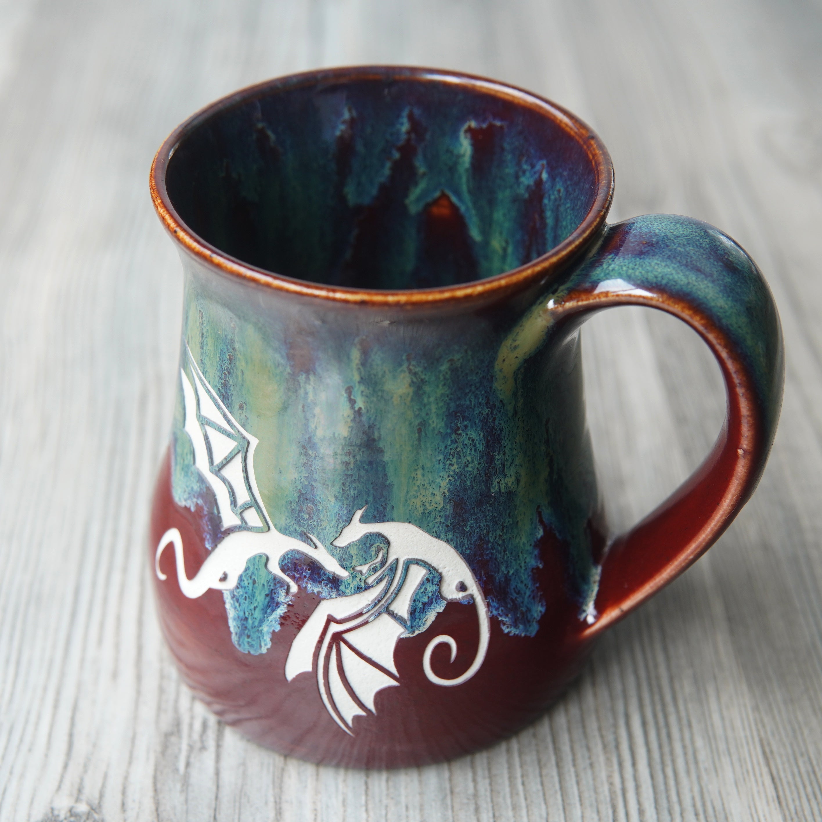 winged dragons engraved on a mug in Fire and Ice colorway, showing glaze dripping down the inside