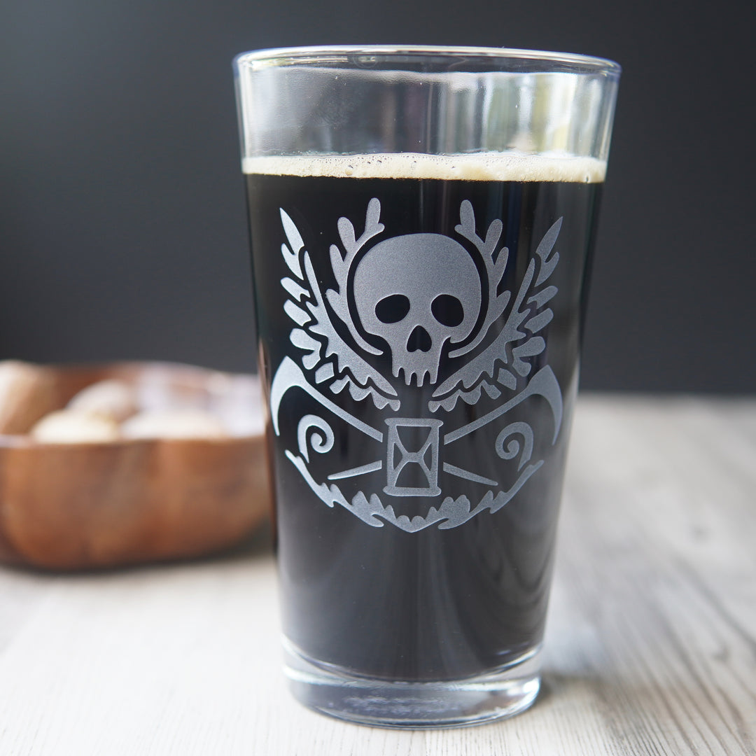 etched pint glass with a winged skull, scythes, and hourglass