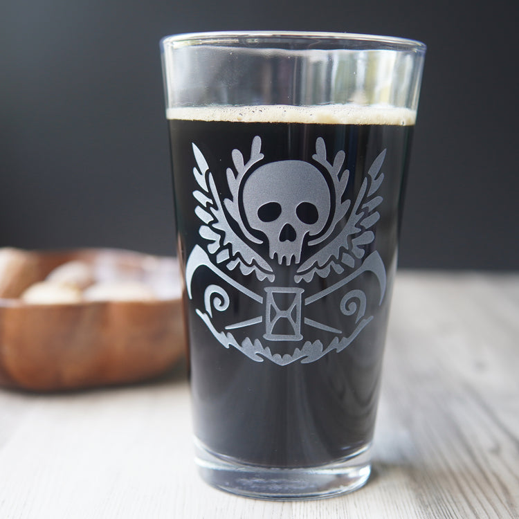 etched pint glass with a winged skull, scythes, and hourglass