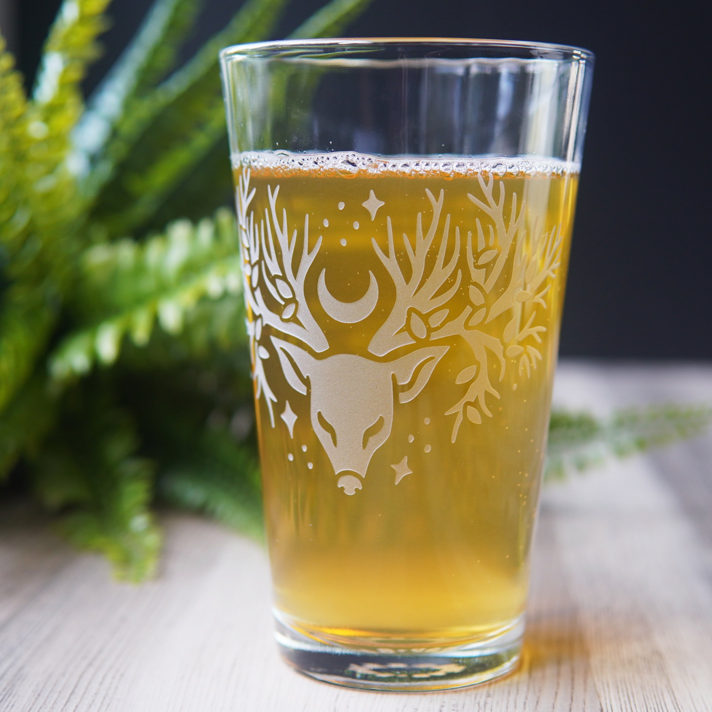 pint glass etched with a deer head whose antlers are tree branches