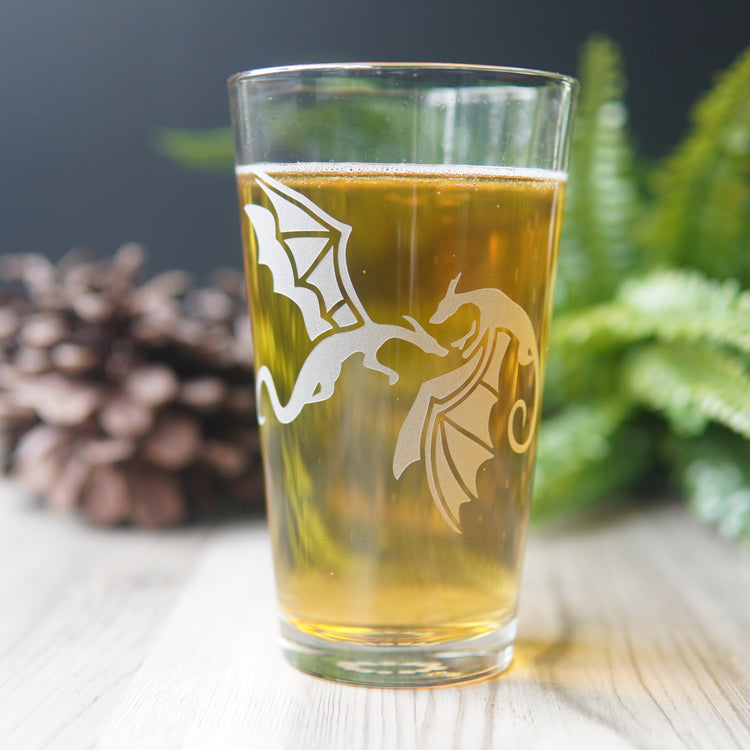 Pint glass engraved with a pair of dragons. They're facing each other, with wings flapping.