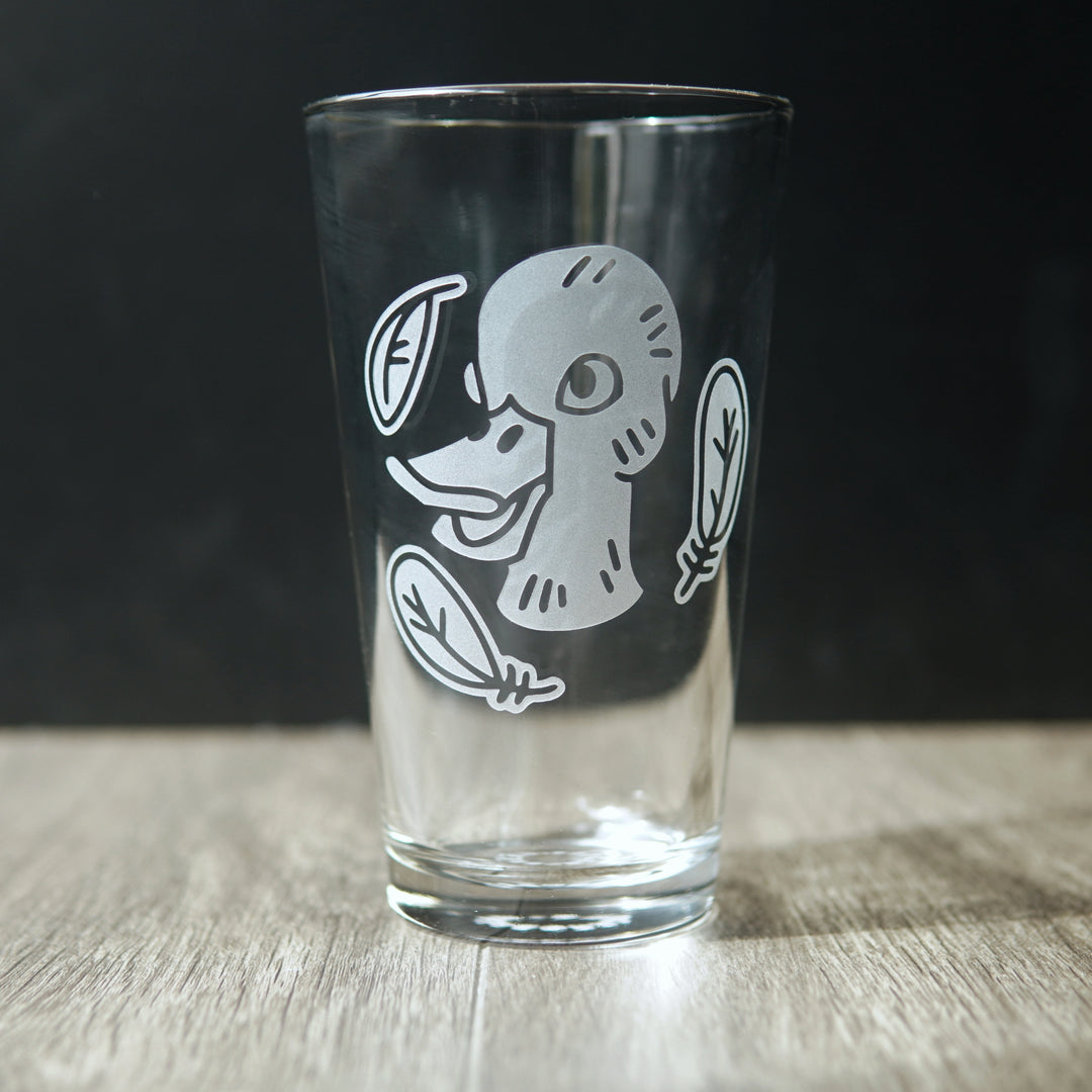 pint glass etched with a duck head, surrounded by three feathers
