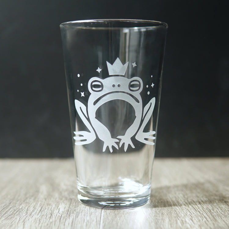 Pint glass etched with a cartoonish frog prince wearing a crown
