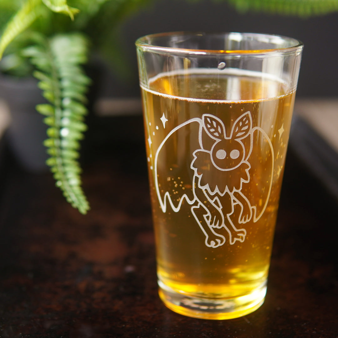 Mothman engraved pint glass full of yellow beer or cider