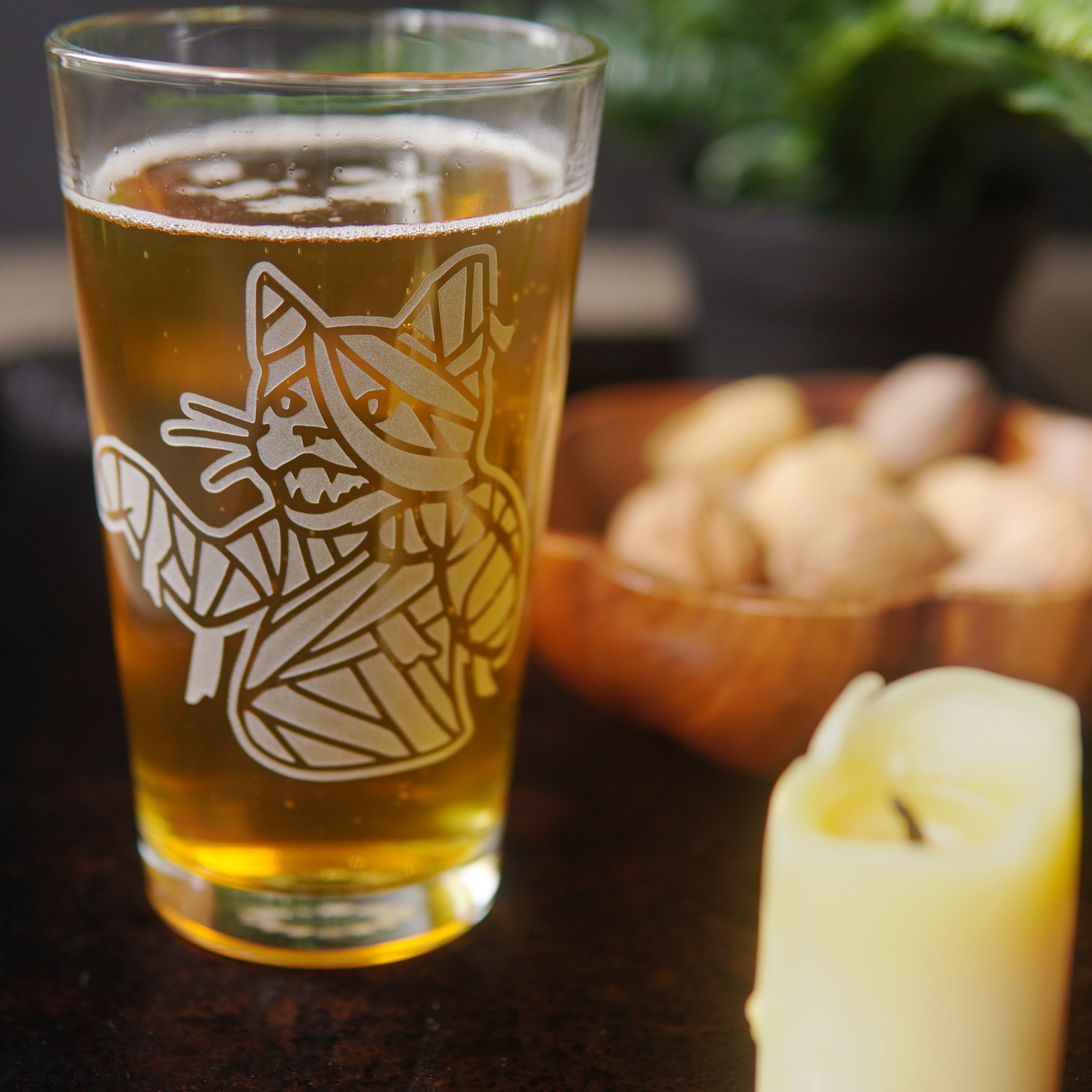 mummy cat pint glass beside a candle and bowl of nuts