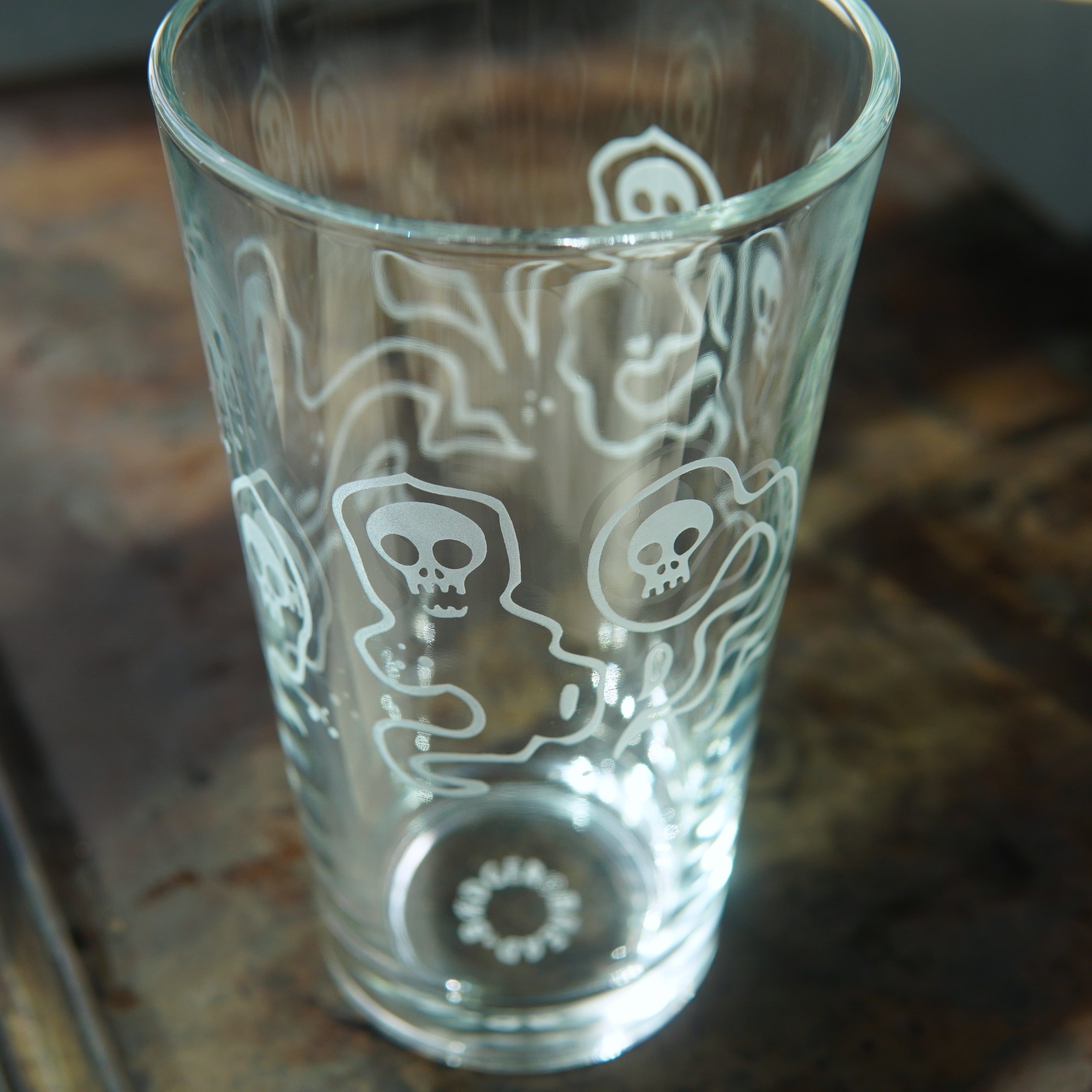 pint glass etched all over with ghosts with skull faces