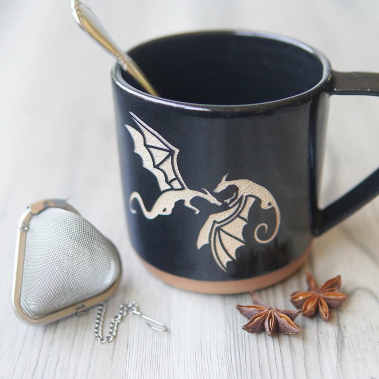 dragons engraved on a black mug, with tea implements