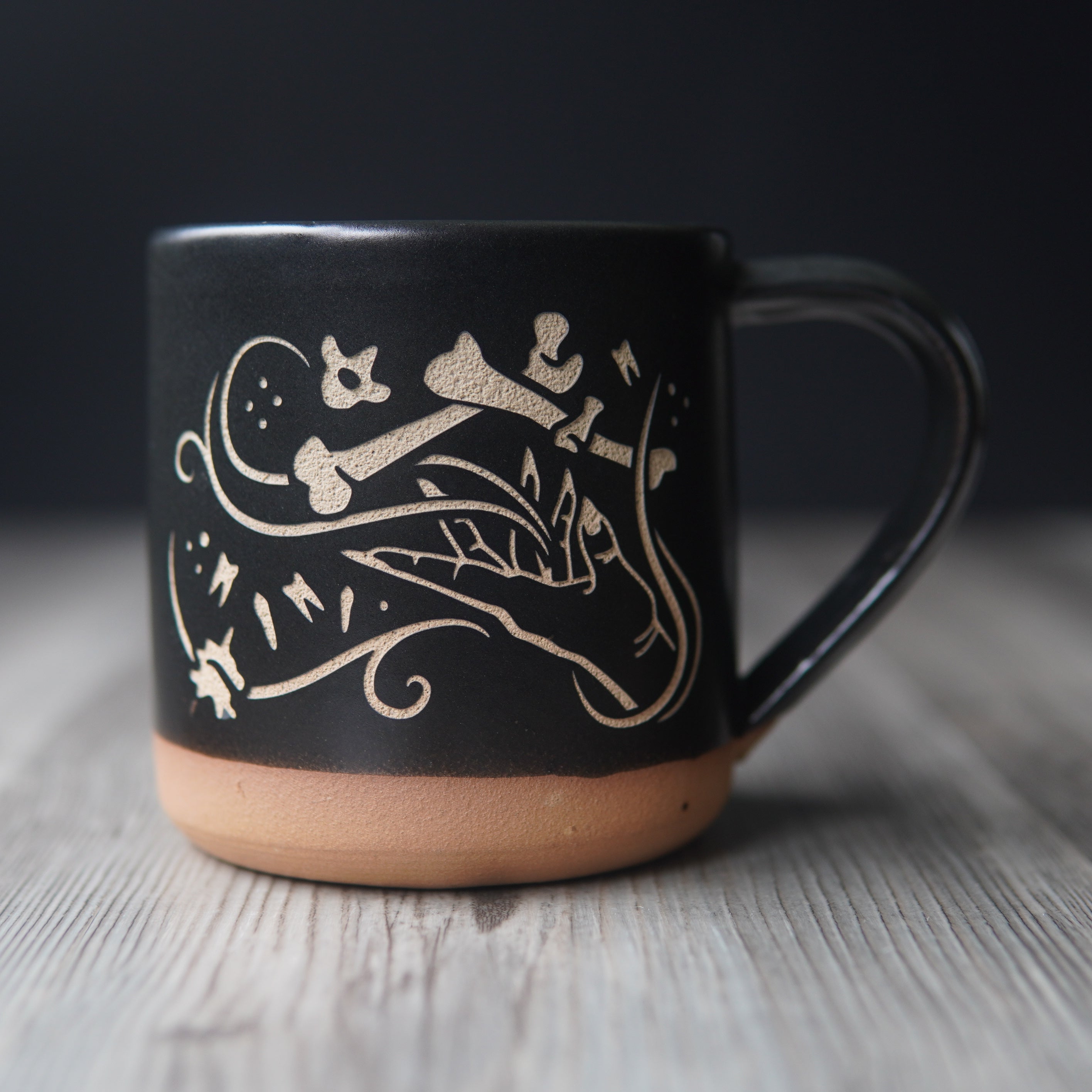 necromancer hand with bones and floating teeth, engraved onto a mug