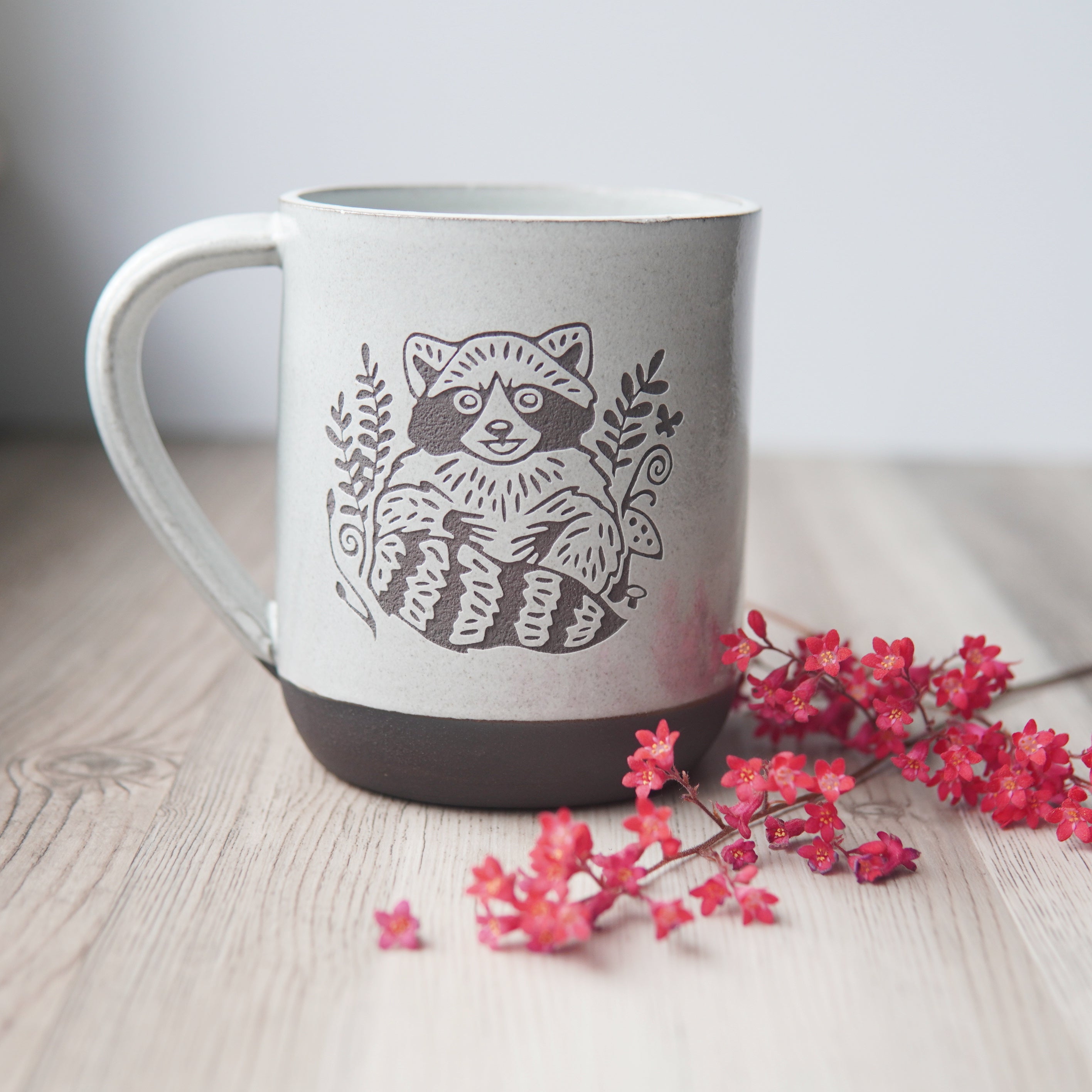 white glaze over chocolate clay mug, engraved with a raccoon