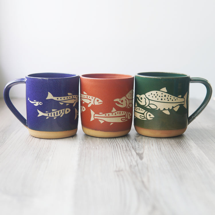Salmon lifecycle mugs in cobalt blue, pine green and paprika red