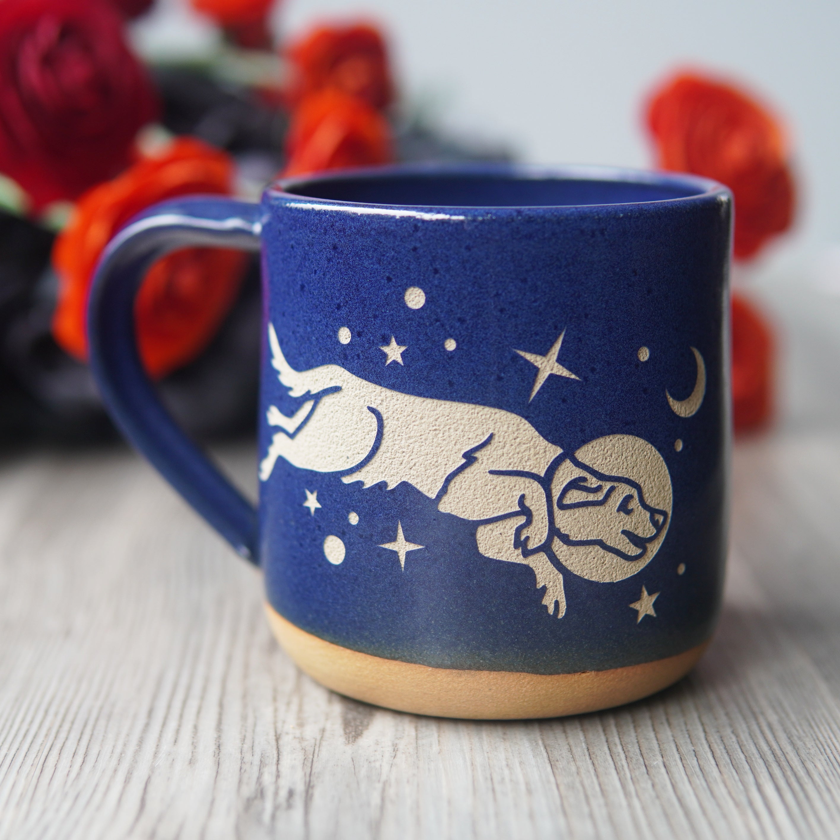cobalt blue space dog mug, with flowers in the background
