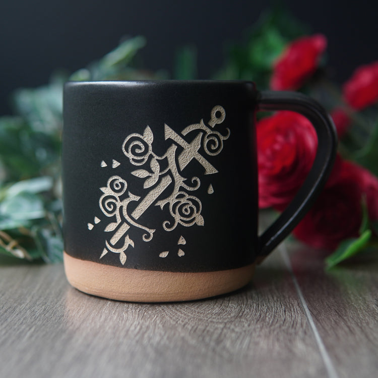 sword wrapped with a vine of roses, engraved on a black mug