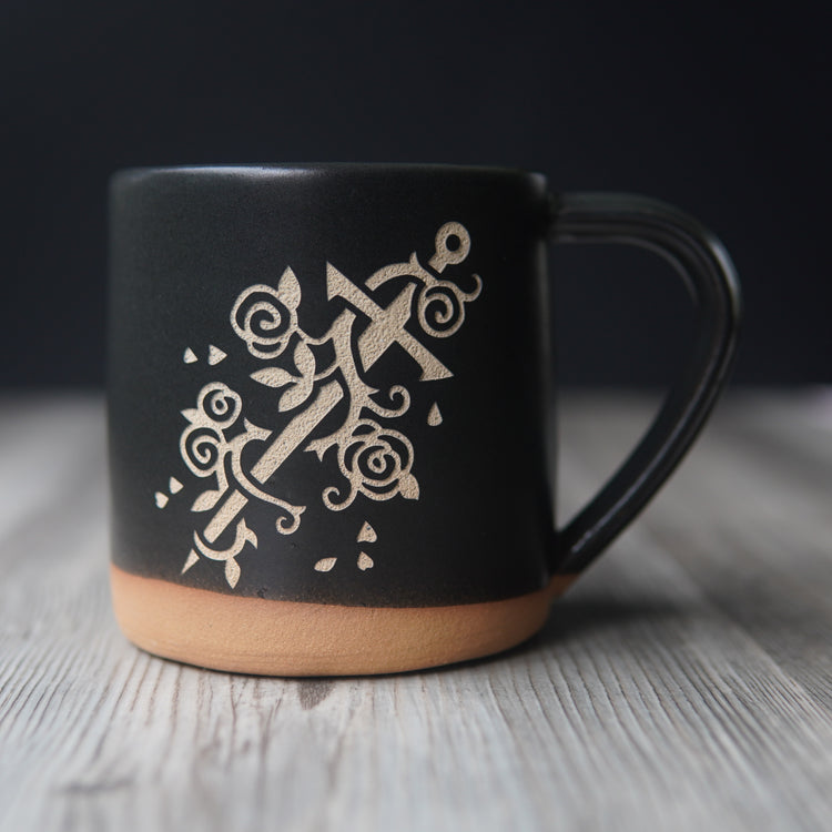 sword wrapped with a vine of roses, engraved on a black mug
