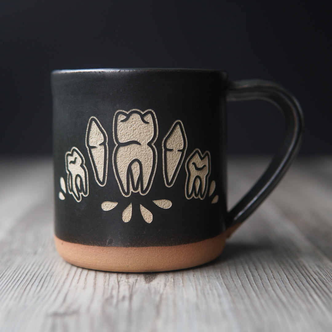 teeth and blood droplets engraved onto a black mug