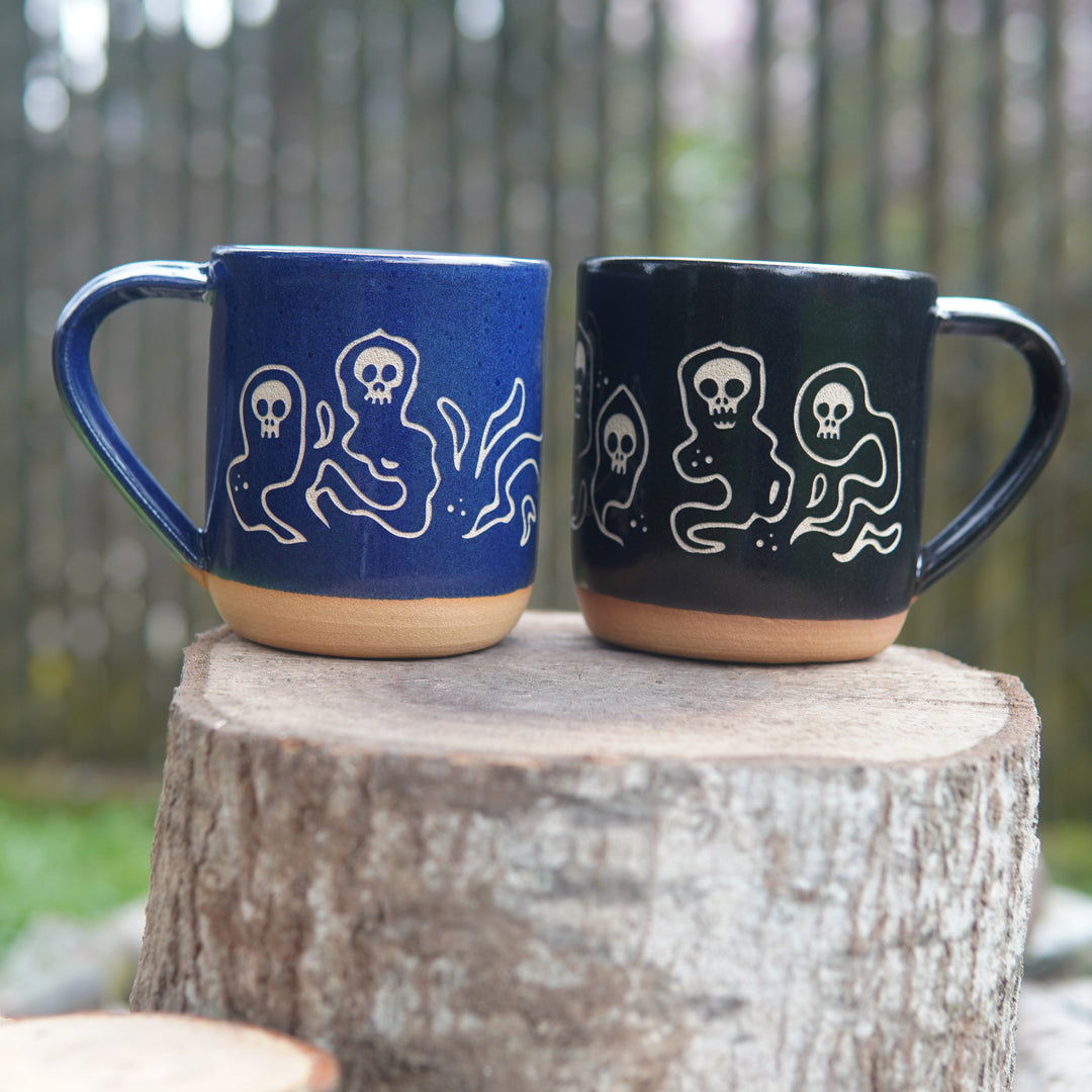 blue and black wraith skull mugs, sitting on a log
