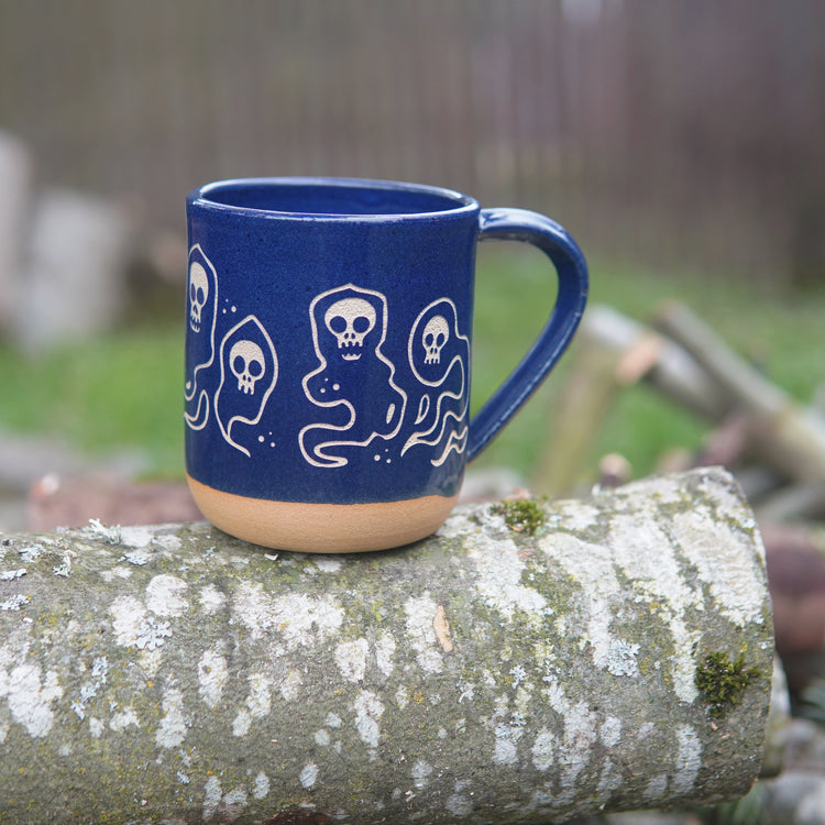 cobalt blue wraith skull mug, sitting on a log