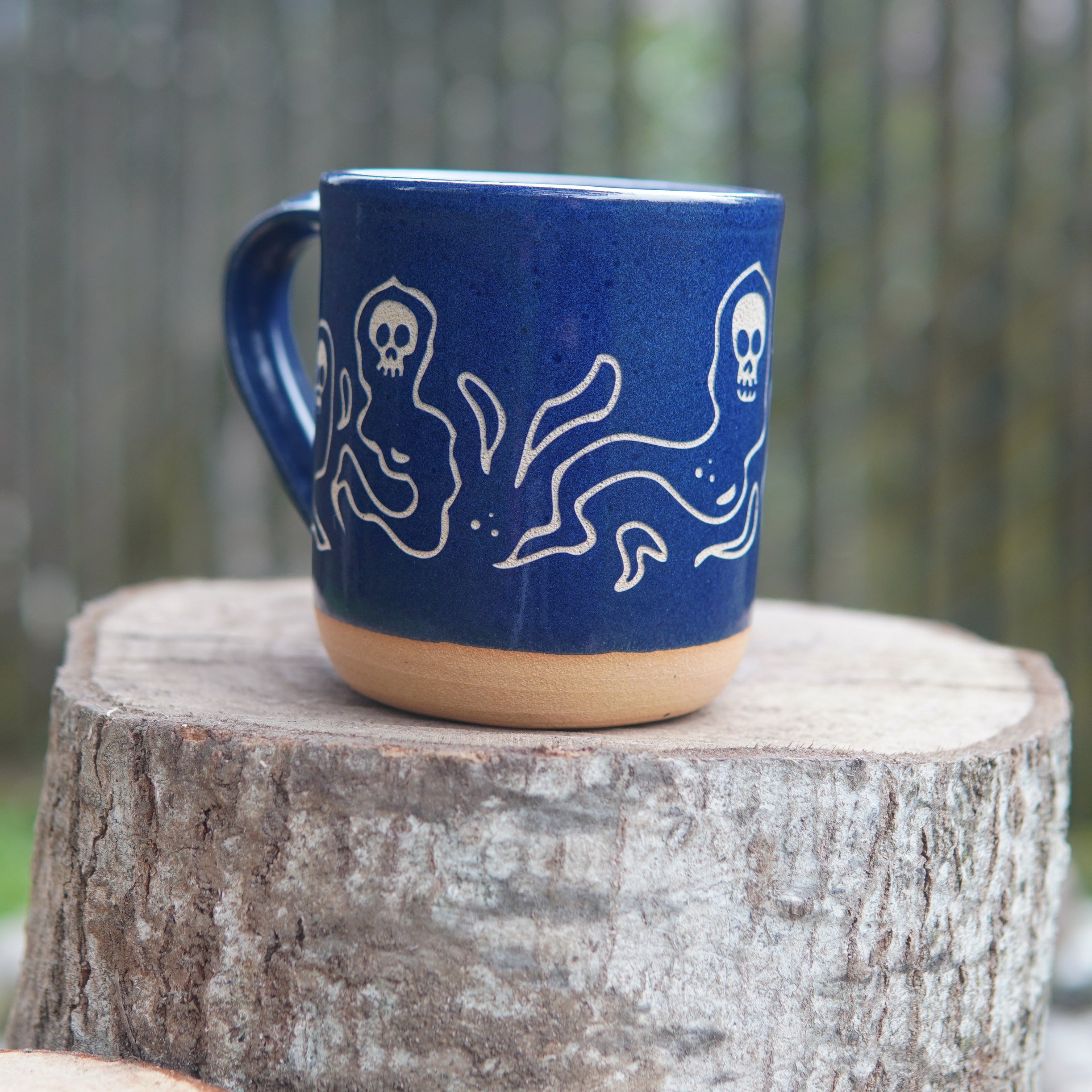cobalt blue wraith skull mug, sitting on a log