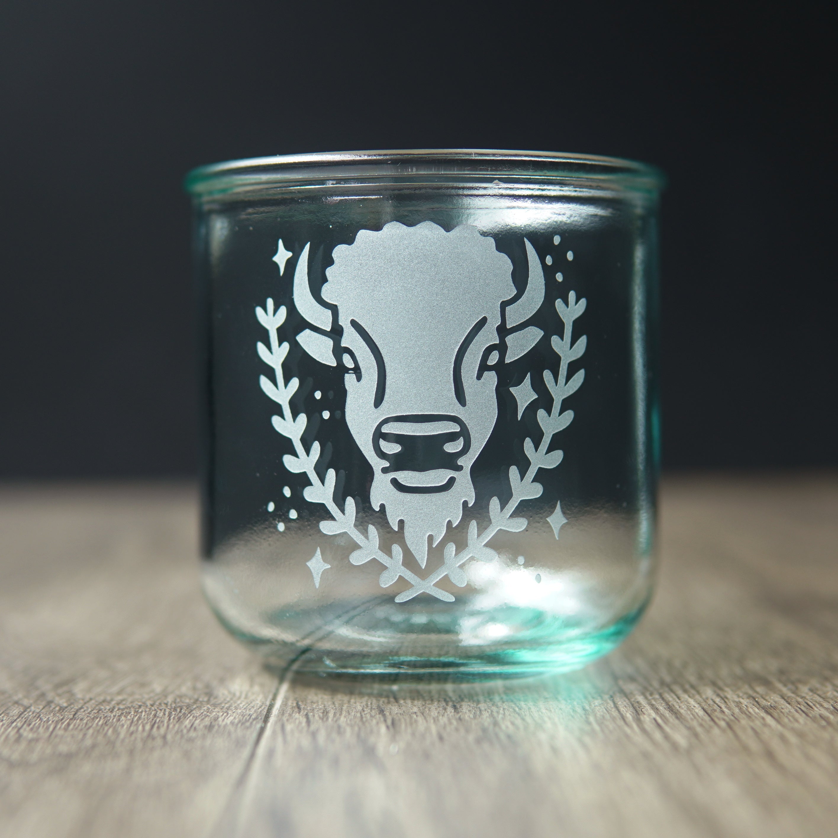 Bison engraved on a short blue-tinged recycled glass cup