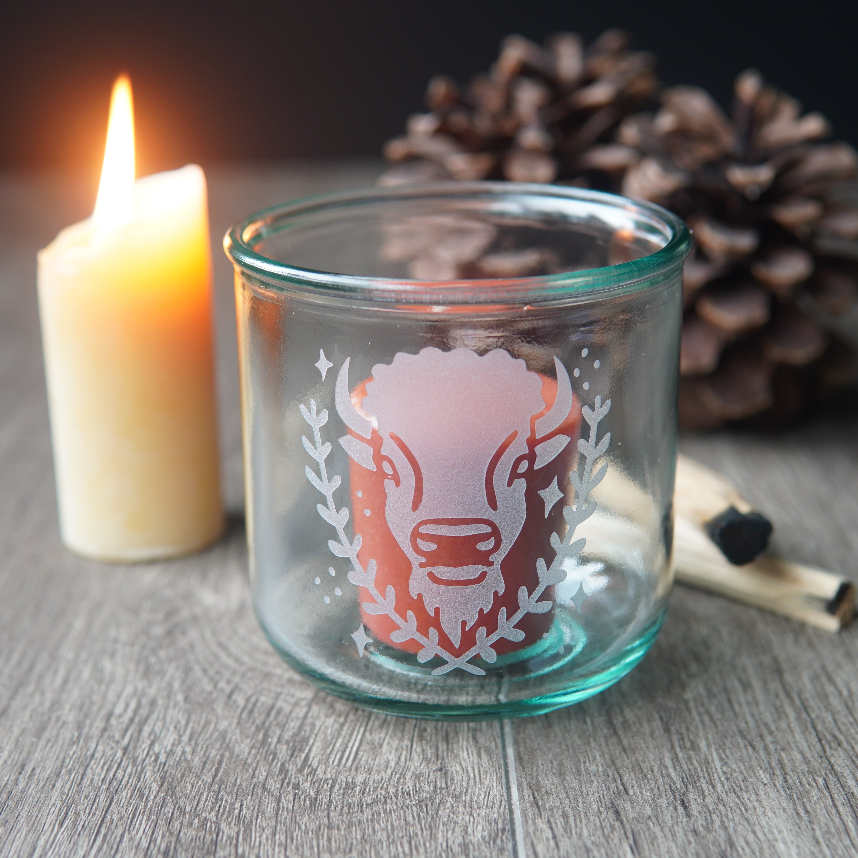 buffalo engraved on a short blue-tinged recycled glass cup, with a votive candle inside
