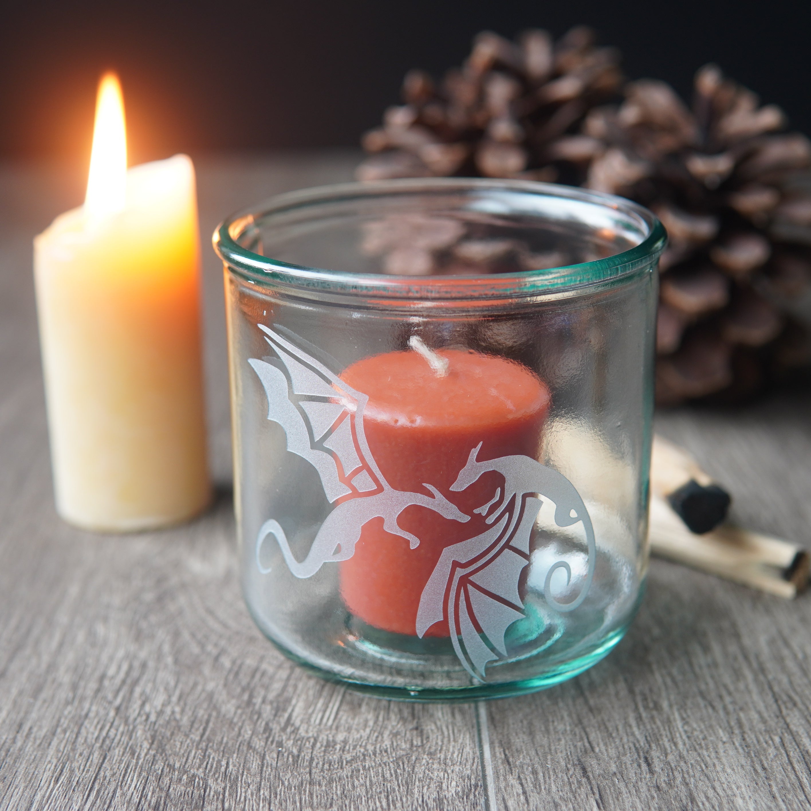 winged dragons on a short glass with a votive candle inside it