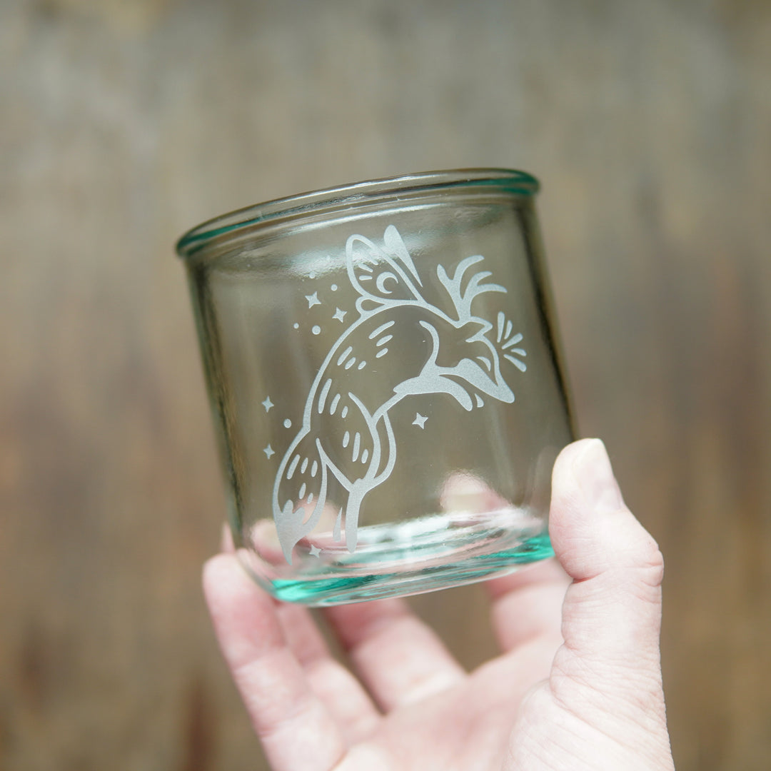 Fox with fairy wings etched onto a short glass, held by a hand