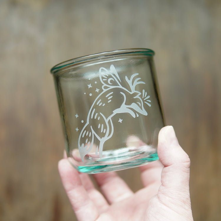 Fox with fairy wings etched onto a short glass, held by a hand