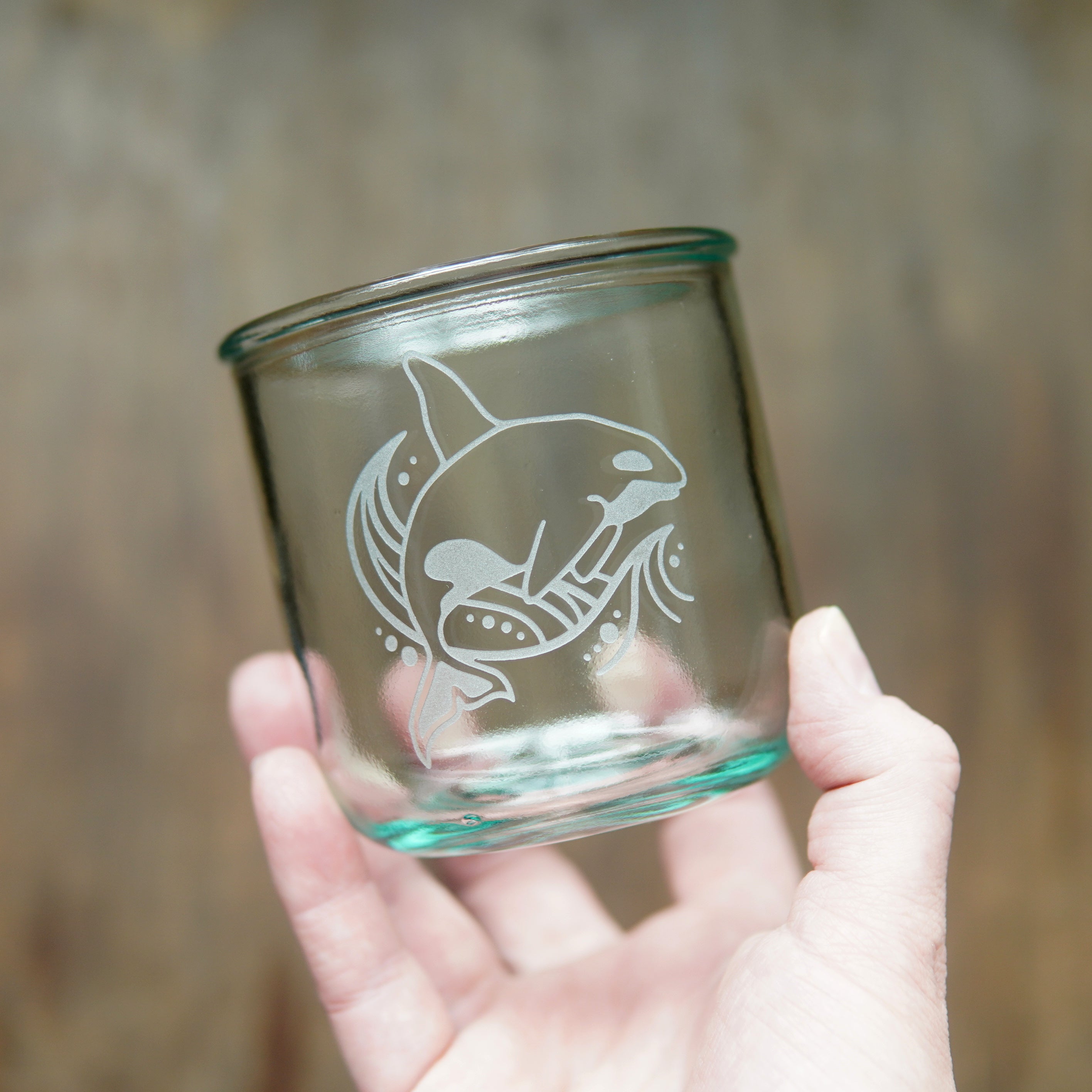 a hand holding an orca whale short glass