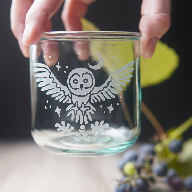 owl engraved short glass held from above by fingers