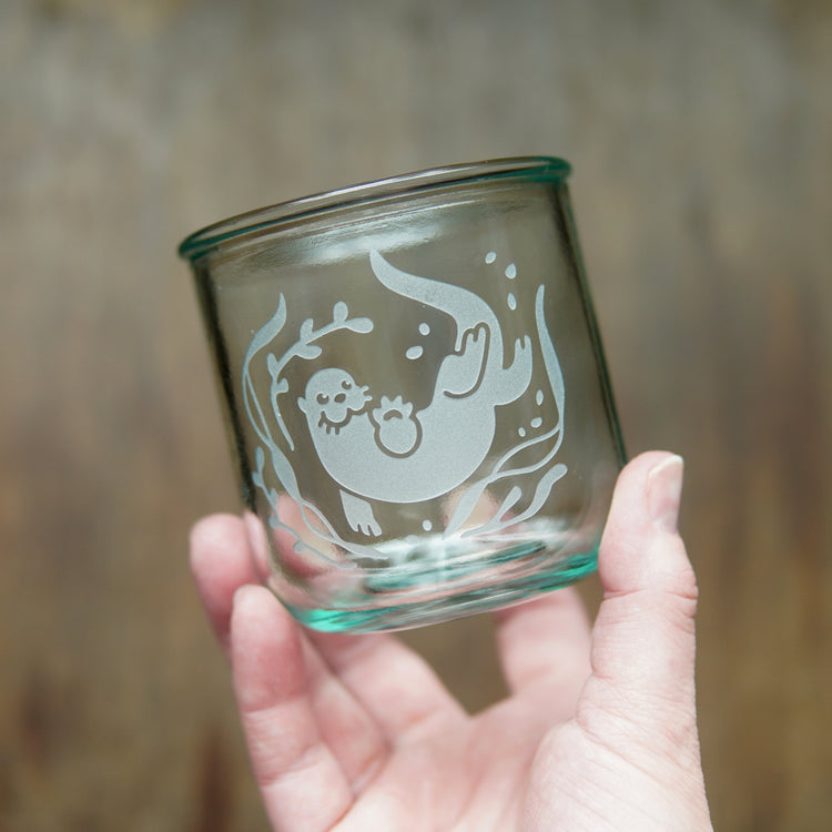 short otter glass held by a hand