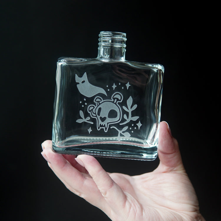 ghost cat and skull growing mushrooms engraved onto a square glass bottle
