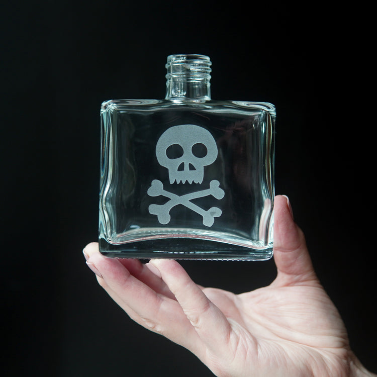skull and crossbones etched onto a square glass bottle