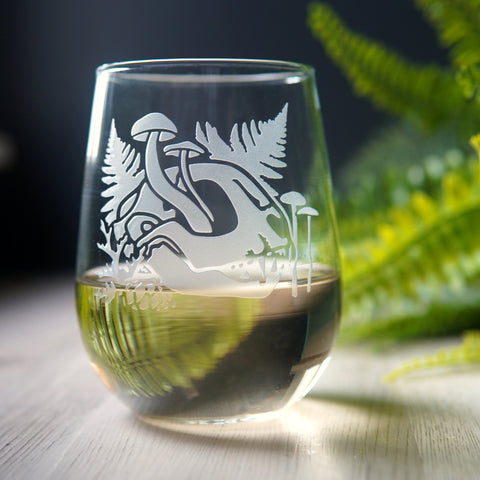 stemless wine glass engraved with a cat skull, mushrooms, and ferns