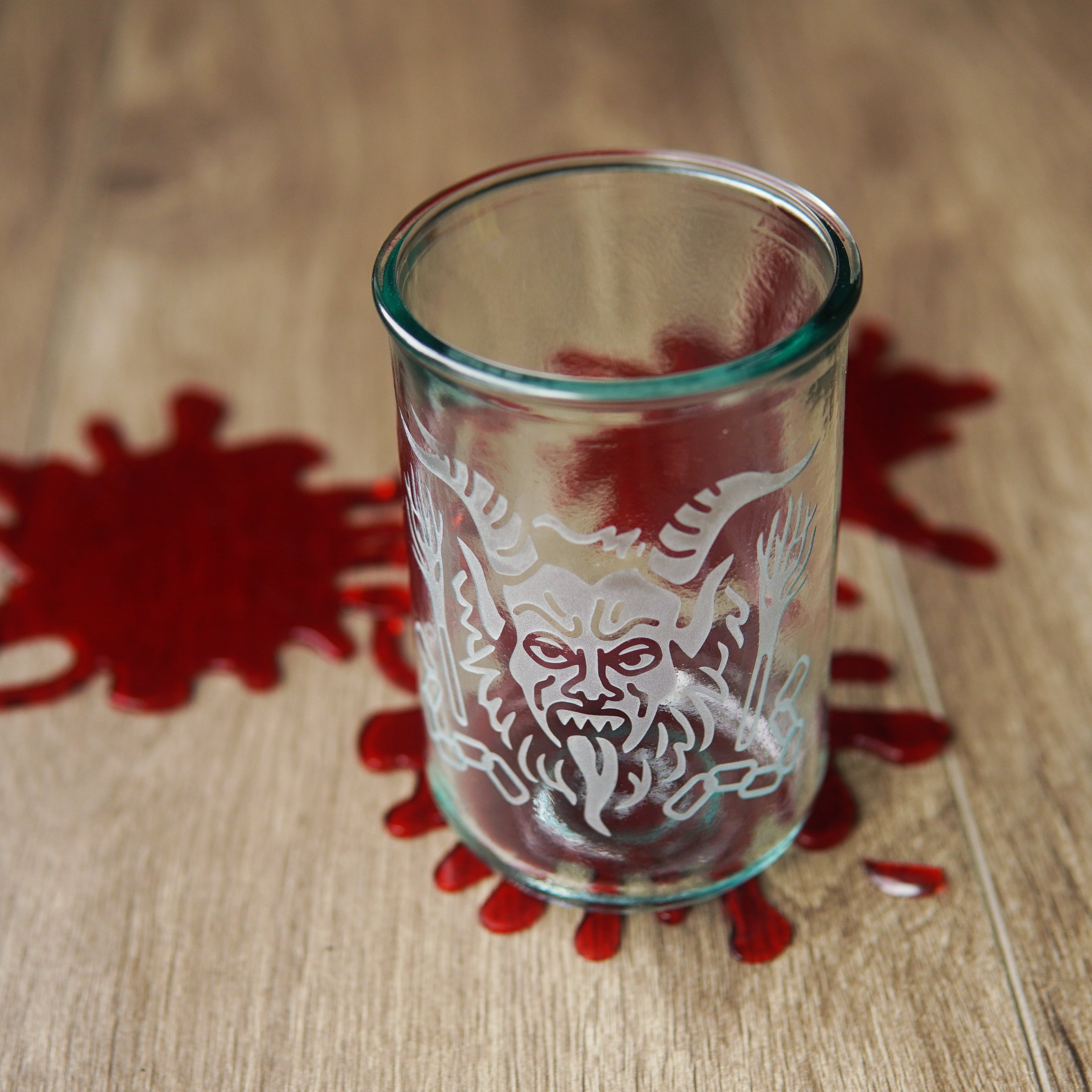 krampus engraved on a tall glass with black fake blood spatters