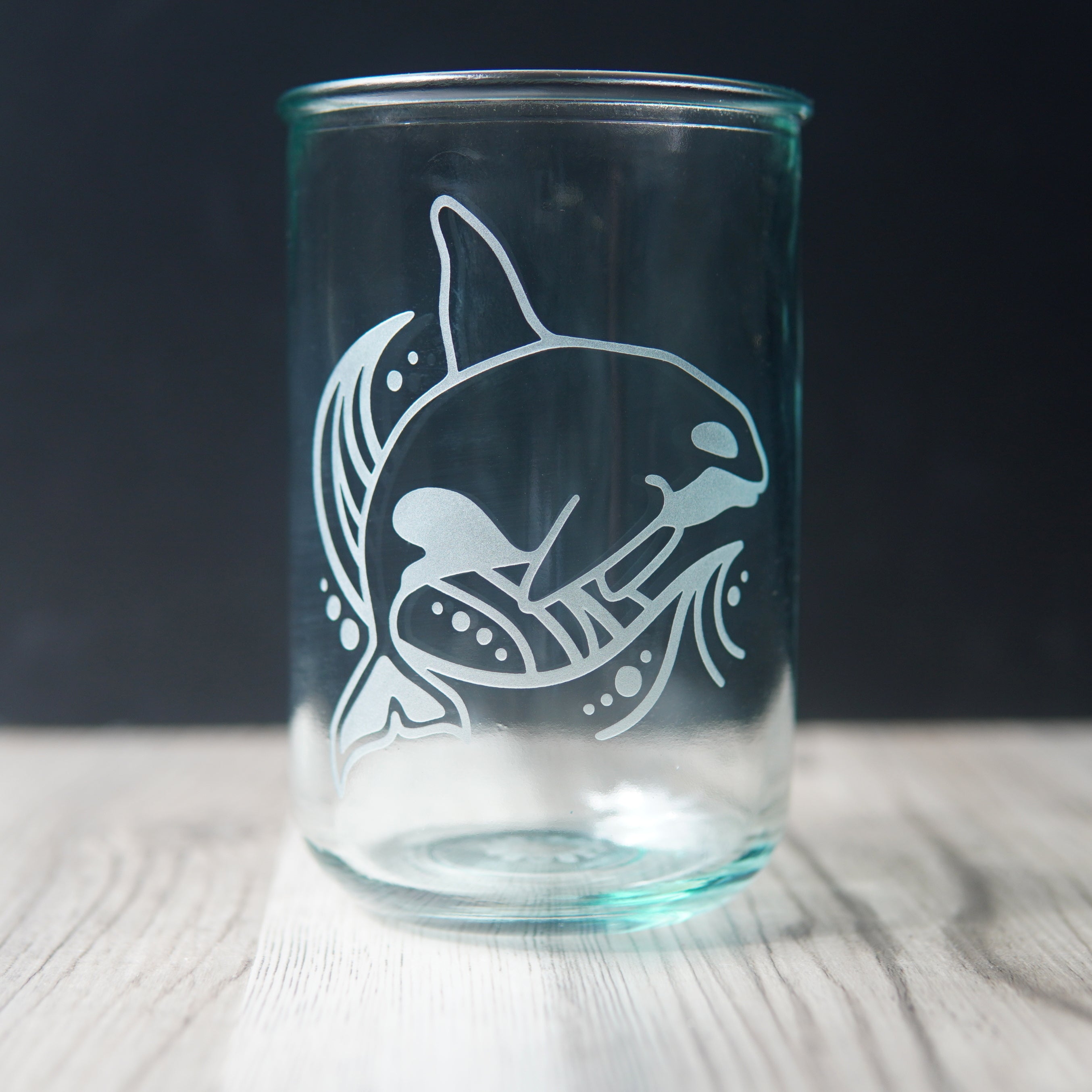 orca whale and stylized waved etched onto a tall glass