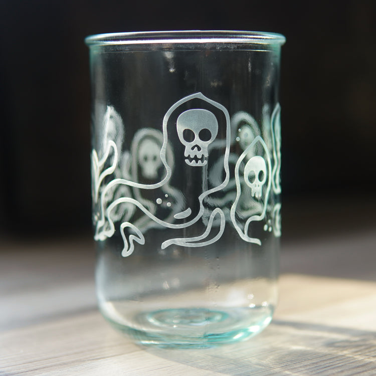 floating skull ghosts etched around a tall glass