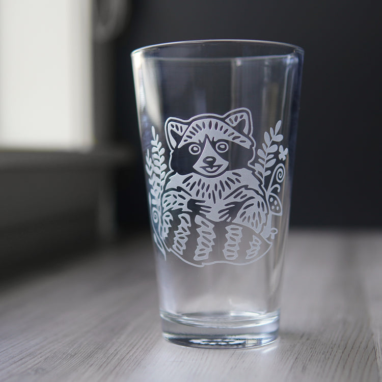 pint glass etched with a cute, smiling raccoon