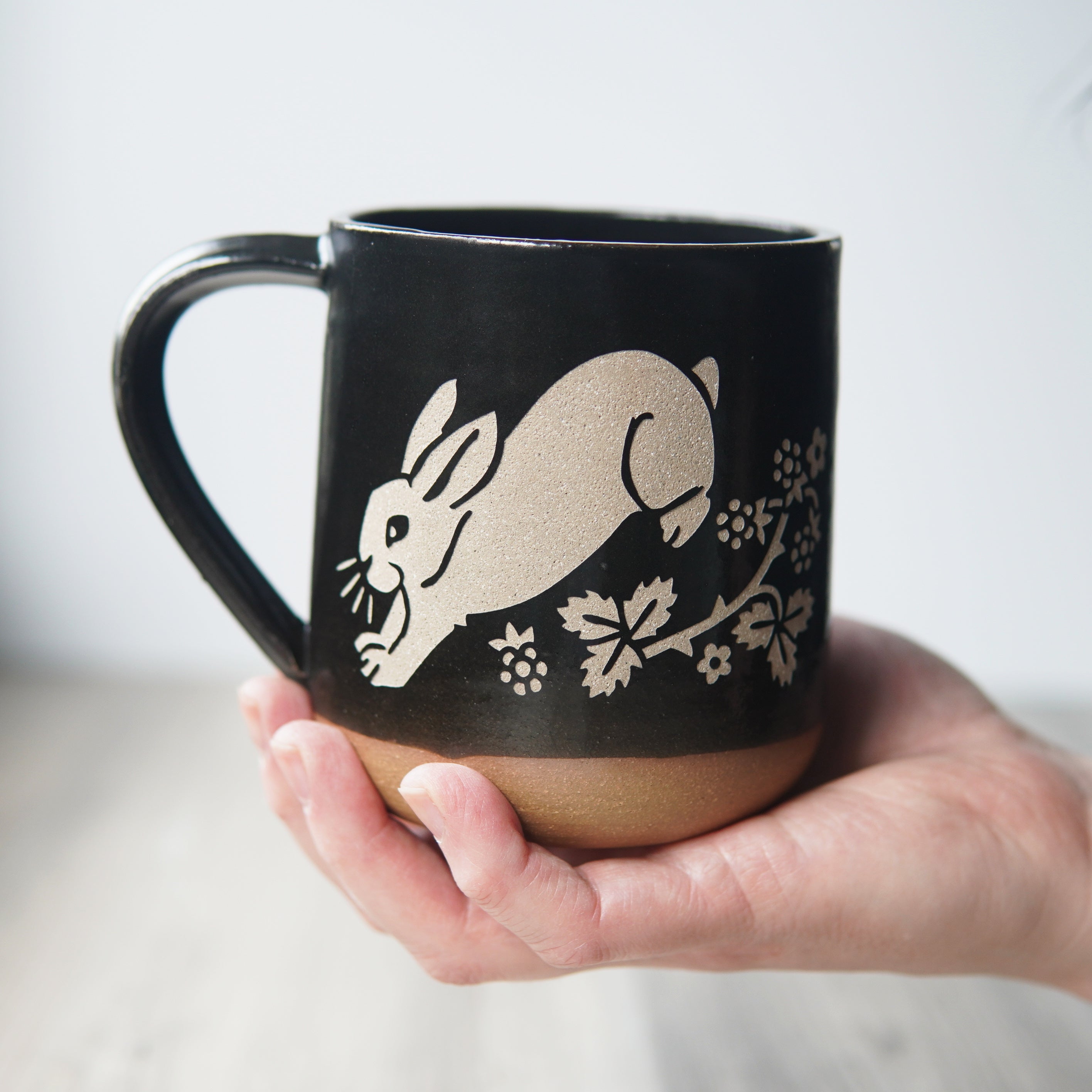 rabbit mug in black, held by a hand