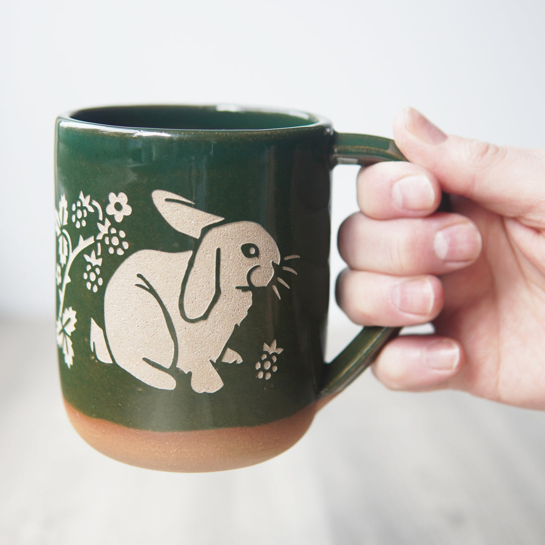 pine green rabbit mug, held by a hand