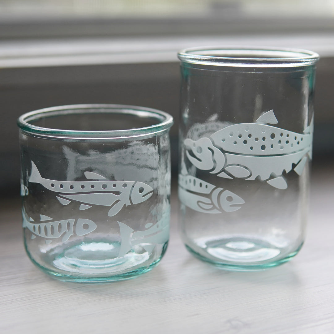 Salmon at different life stages engraved around a short and tall glass