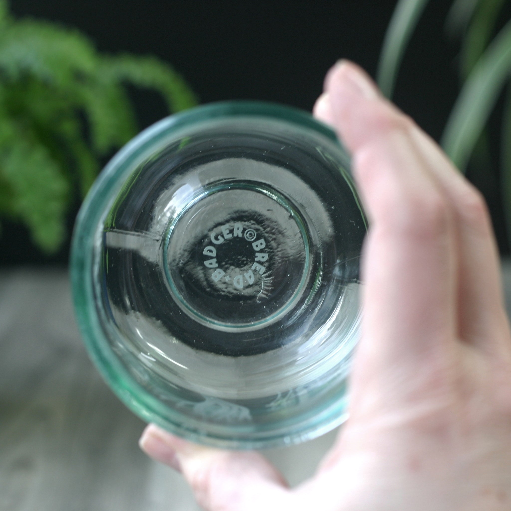the bottom of glass tumbler with the Bread and Badger logo, readable as seen from the inside of the glass