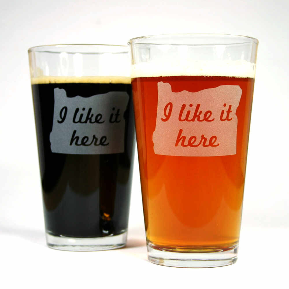 pair of Oregon "I like it here" etched pint glasses full of beer