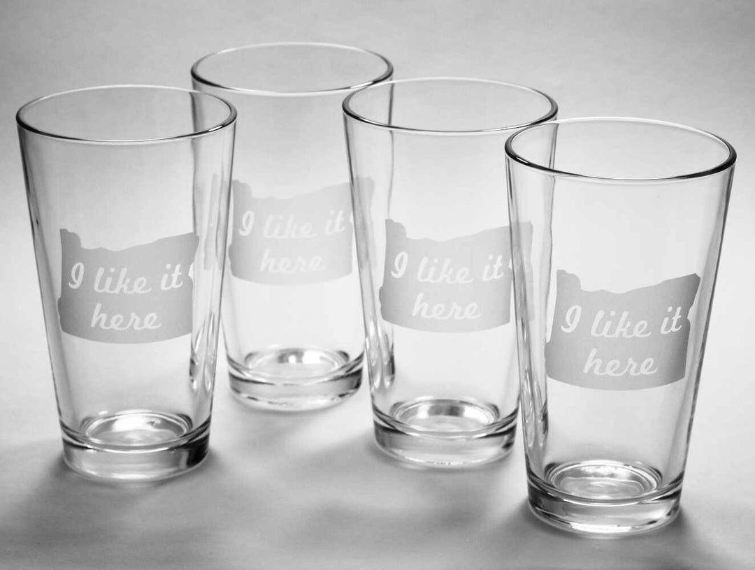 4 clear pint glasses etched with the state of Oregon and the words "I like it here" inside the state