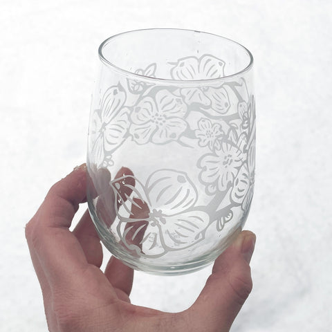 dogwood flower branches engraved stemless wine glass in front of snow