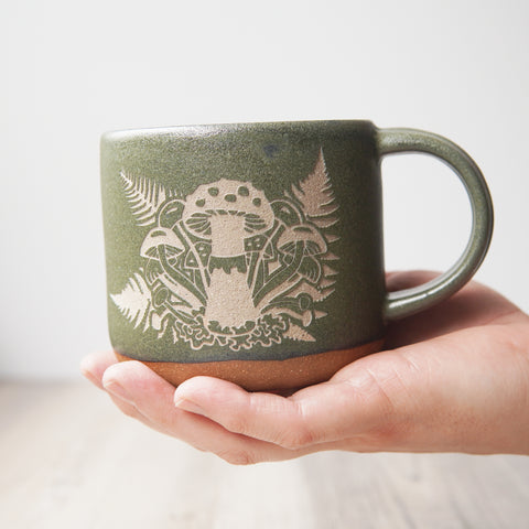 Mushroom + Ferns engraved mug in Moss green, held in a hand