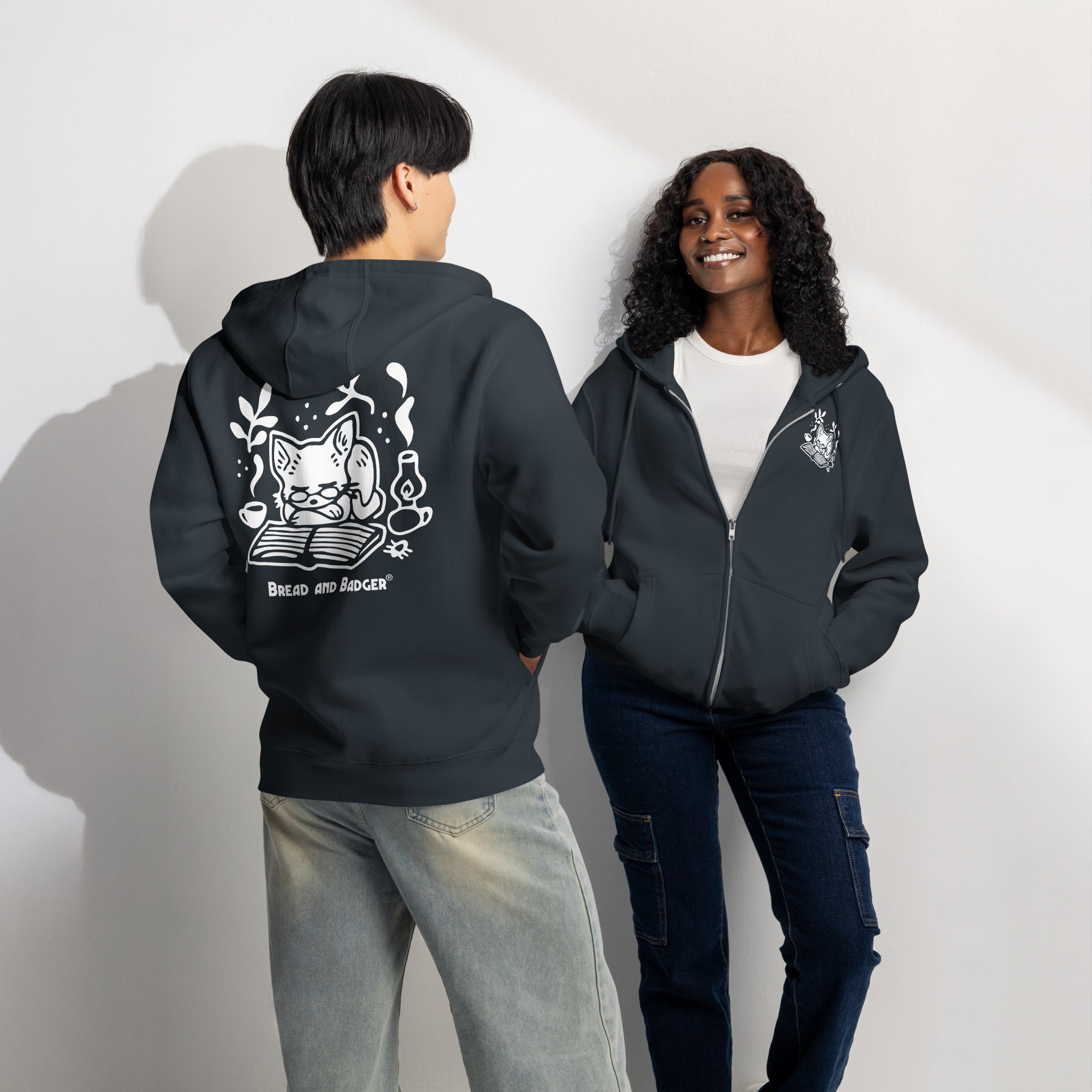 Two people wearing navy hoodies with white graphics on a plain background