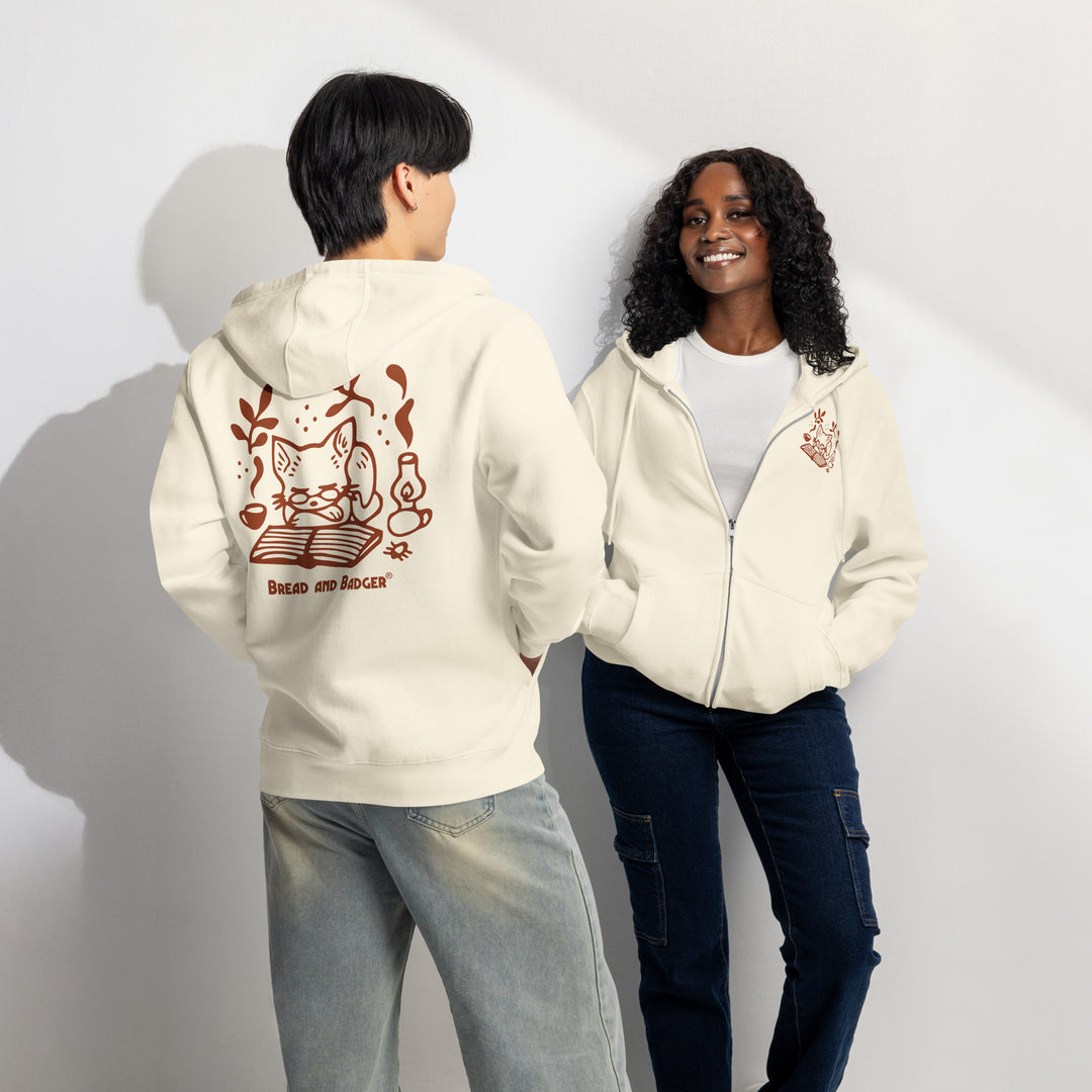Two people wearing light tan "sandshell" colored hoodies with rust-red graphics on a plain background