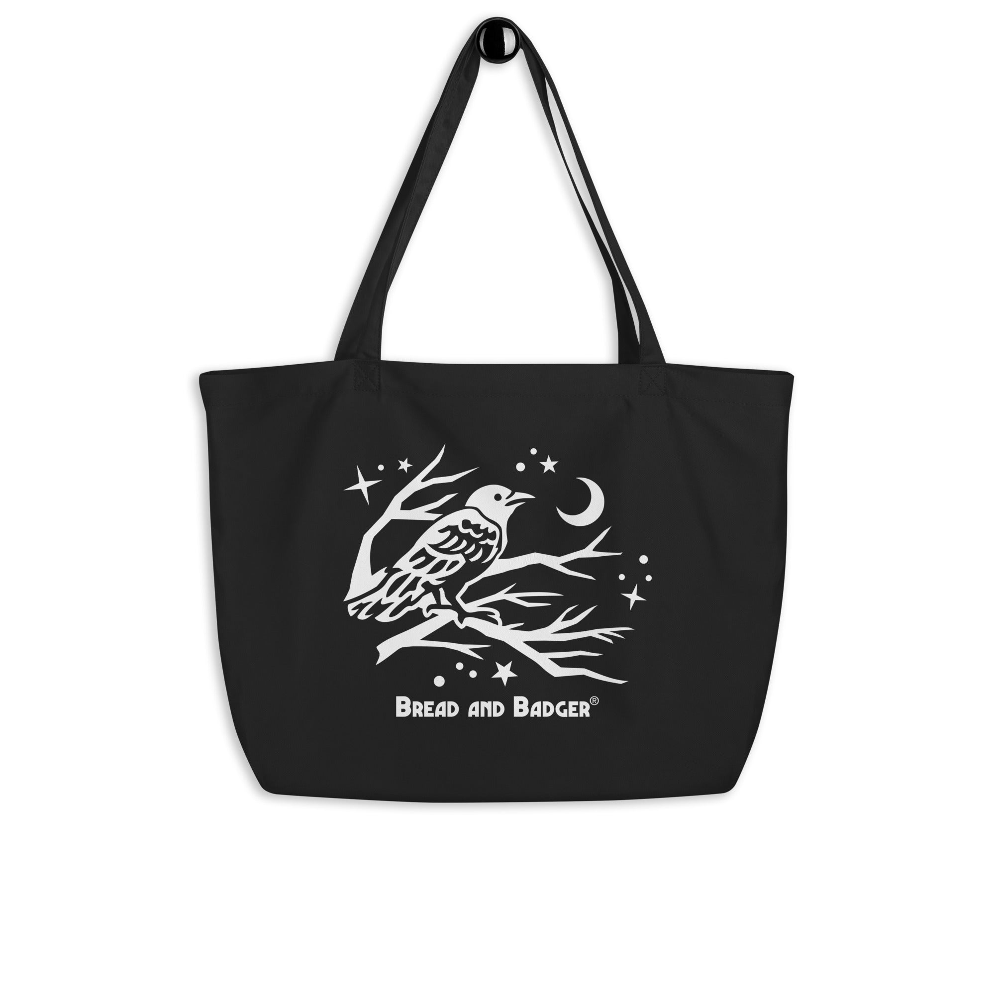 Black tote bag with white crow in a tree design and 'Bread and Badger' text on a white background